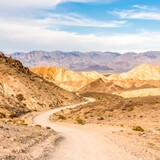 Winding dirt road through colorful desert mountains