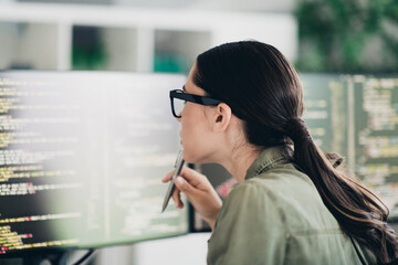 Charming female programmer analyzing code on screen in a modern workspace, focused on debugging and enhancing software