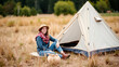 © Cameron - Young woman sitting by tent in field
