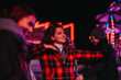 © qunica.com - Friends share joyful moments and laughter on a winter evening under festive lights. Capturing warm connections and the spirit of friendship during outdoor nighttime celebrations.