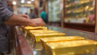 © Nakarin - Gold bar price surge excites investor hands checking shiny gold bars in jewelry store display