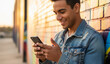 © Metehan - Smiling young man holding phone while text messaging