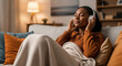 © Elenba - Young woman listening music in headphones on couch, relaxing at home. Listening music helps her unwind after a long day, so she can find peace and quiet.