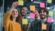 © Anas - Collaborative brainstorming session with diverse young professionals using sticky notes on glass wall.