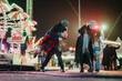 © qunica.com - A lively setting featuring friends enjoying a fun night at an amusement park filled with festive lights and rides, showcasing joy, laughter, and connection during a cheerful holiday atmosphere.