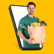 © New Africa - Delivery service worker giving online order out of mobile phone against orange background. Man with paper bag full of food products