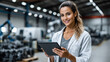© Николай Срибяник - A confident and happy female engineer in a lab coat smiles while holding a digital tablet in a modern factory setting, symbolizing innovation and career success.