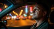 © photoplotnikov - Caucasian male adult driving at night with city lights in background
