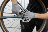A person is skillfully repairing a bicycle's disc brake in a well-lit bike shop. ensuring a safe and efficient fix for riders.