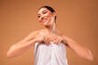 © Beauty Hero - Beautiful young woman wrapped in a white towel on beige background, smiling confidently