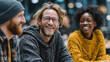 © VICHIZH - A candid group portrait of three friends laughing and chatting indoors, warm lighting, cozy sweaters, and a genuine connection that captures friendly urban lifestyle.