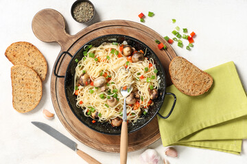 Wall Mural - frying pan with tasty pasta, mushrooms and bread on light background
