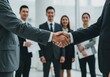 © Abdullah - Business Handshake with Man in Grey Suit and Blurred Standing Colleagues Behind