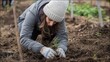 © Adriana - Woman planting trees or working in community garden promoting local food production and habitat restoration, concept of Sustainability and Community Engagement