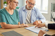 © Studio Romantic - Confident senior couple sitting with financial advisor in office for consultation, signing documents and discussing insurance in retirement. Elderly man and woman sitting with male agent.