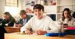 © peopleimages.com - Smile, writing and portrait of teenager in classroom for learning, education or development. Happy, books and face of boy with studying at high school for test, exam or assignment on campus.