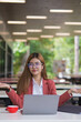 © maeching - Asian businesswoman using digital laptop while standing in front of modern building. Attractive female employee working in front of office.