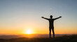 © Airwj - Silhouette of a person with arms outstretched at sunrise over a mountain range.