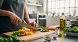 © Dura - Woman chopping fresh vegetables on wooden board in bright kitchen preparing healthy meal with focus and care.