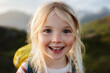 © EVERST - Child girl happy smiling face 5 years old kid hiking with backpack outdoor portrait looking at camera close up blonde hair family travel vacations candid emotions