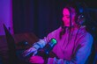 © deagreez - Addicted gamer woman gamer with headset and microphone live streaming at home using laptop in neon lights for online gaming