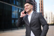 © muse studio - Business professional in contemporary suit engaged in a lively phone conversation outdoors