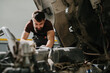 © dsheremeta - Professional auto mechanic repairing truck engine in garage