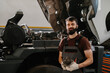 © dsheremeta - Mechanic holding truck part and smiling in repair shop