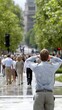 © pvl0707 - Busy city street filled with people walking under trees on a sunny day in an urban area