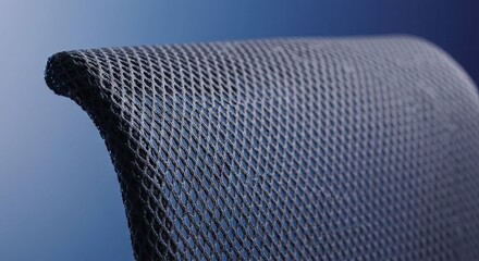 Closeup of a dark curved mesh surface against a blue background showing a uniform grid pattern