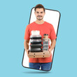 © New Africa - Food delivery service worker giving online order out of mobile phone display. Light blue background