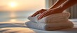 © Nure - Elegant Woman’s Hands Arranging Fluffy Towels on Mattress in Cozy Bedroom with Seaside Sunset