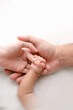 © Vlafy Studio - Parents’ hands gently holding a newborn’s hand on white bedding. High-key lifestyle photo symbolizing love, safety, and early bonding—ideal for parenting, maternity, and healthcare use.