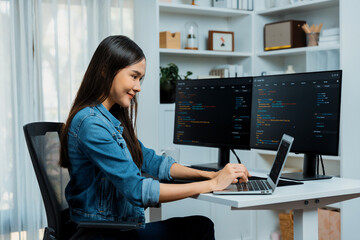 Smiling young Asian in IT developer creating with typing online information on laptop with coding program data of application, wearing jeans shirt. surrounded by safety analysis two screen. Stratagem.