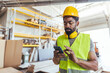 © Dragana Gordic - Construction Worker Inspecting Smartphone in Industrial Warehouse Setting