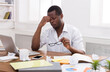 © Prostock-studio - Overworking african-american employee in office. Tired and having headache while working on a new project