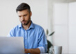 © Prostock-studio - Concentrated businessman working on laptop at workplace in office, male entrepreneur looking at computer screen and typing on keyboard, filling report, answering emails, managing project, copy space