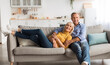 © Prostock-studio - Mature Spouses Hugging Sitting On Sofa Together At Home, Smiling To Camera. Happy Senior Husband And Wife Embracing Relaxing On Couch On Weekend. Retirement Lifestyle And Happiness In Marriage