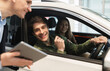 © Prostock-studio - Young Caucasian couple clarifying car purchase details with salesman, looking at tablet screen in dealership center. Happy millennial spouses buying new vehicle at automobile showroom