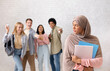 © Prostock-studio - Upset lonely woman suffering from bullying and racial discrimination. Multiracial students throw paper at muslim lady with notebooks in college on brick white wall background , studio shot, free space