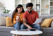 © Prostock-studio - Indian Married Couple Planning Budget Together, Reading Papers And Calculating Spends While Sitting On Couch In Living Room, Young Eastern Spouses Checking Documents And Accounting Taxes, Free Space