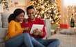 © Prostock-studio - Home cozy in New Year and Christmas and video call to friends or family. Happy millennial african american lovers guy and lady talking on digital tablet in living room interior with tree with garlands