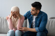 © Prostock-studio - Middle-eastern bearded man comforting his crying wife, young muslim couple having problems in relationships, visiting family therapist together. Frustrated lady in hijab feeling unhappy
