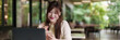 © snowing12 - Asian young woman freelancer remote work outdoor cafรฉ setting using laptop smartphone digital content creation productivity