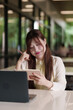 © snowing12 - Asian woman freelance professional remote working cafe planning creative project using laptop tablet thinking ideas modern space