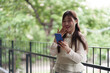© snowing12 - Asian adult woman enjoys smartphone outdoors remote work break happy moment digital communication vibrant green environment urban balcony lifestyle