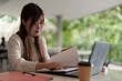 © snowing12 - Asian adult woman freelancing remotely working outdoors reviewing documents laptop computer professional career lifestyle modern workspace