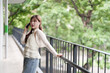 © snowing12 - Asian young adult professional woman taking important phone call outdoor city urban nature setting freelance work remote business management