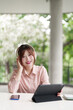 © snowing12 - Asian adult woman remote work outdoors using tablet headphones professional freelancer lifestyle digital nomad smart technology connectivity