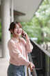 © snowing12 - Cheerful Asian young adult woman talking phone outdoor smiling enjoying break freelance remote work global communication technology connect